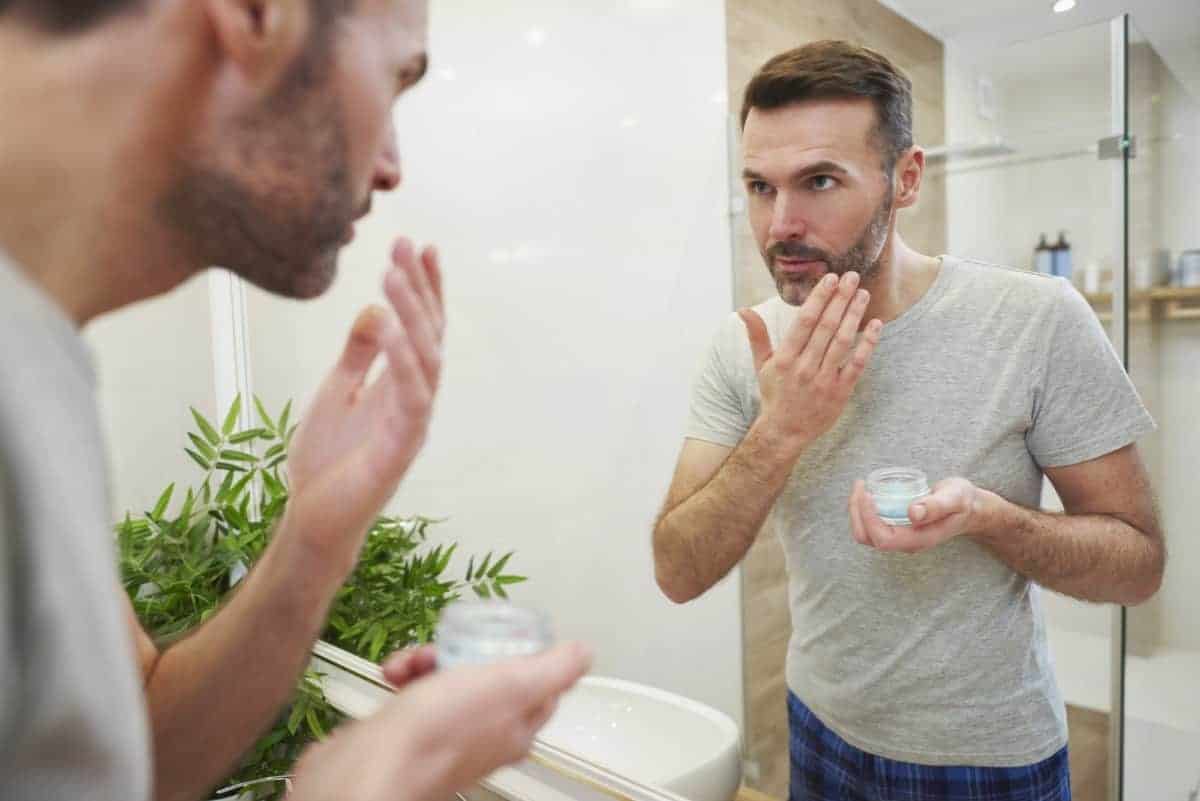 Man applying face cream on his face in bathroom